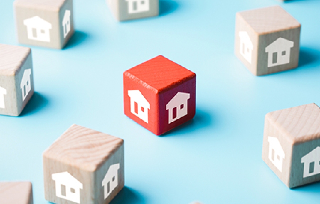 Unique red wooden block in group of wooden blocks with house icons on blue background, select the house or real estate concept